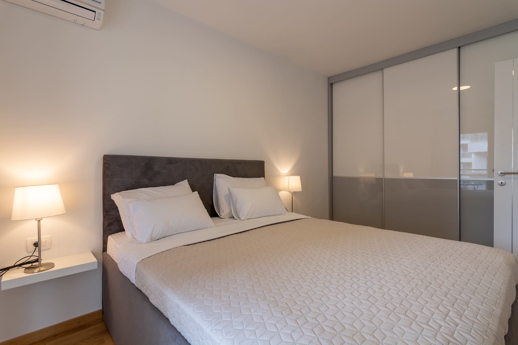 Udobna spavaća soba sa toplim osvjetljenjem u Cozy Seaside apartmanu